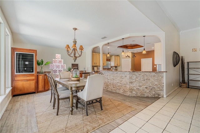 15929 San Felipe Dr, Corpus Christi, TX 78418 - dining room featuring a chandelier, light wood-style flooring, crown molding, and arched walkways