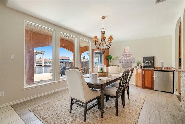 15929 San Felipe Dr, Corpus Christi, TX 78418 - dining area featuring a chandelier, light wood-style flooring, arched walkways, and baseboards