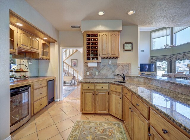 kitchen featuring tasteful backsplash, a notable chandelier, light stone countertops, light tile patterned flooring, and kitchen peninsula