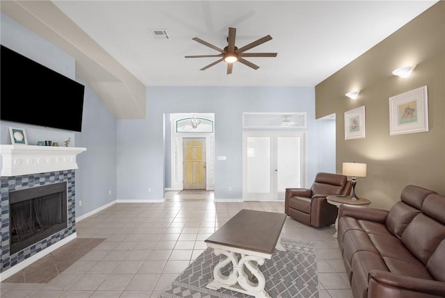 living area with a ceiling fan, light tile patterned flooring, a tile fireplace, and baseboards