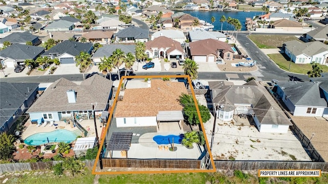aerial perspective of suburban area featuring property parcel outlined, a pool, and a large body of water