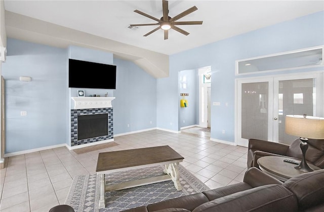 living area with a ceiling fan, tile patterned floors, a fireplace, and baseboards
