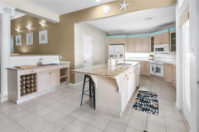 kitchen featuring white appliances, a sink, light tile patterned floors, and tasteful backsplash