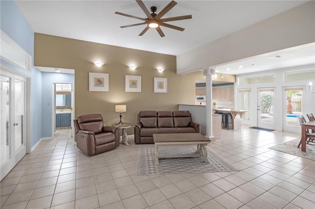 living area featuring light tile patterned floors, a ceiling fan, healthy amount of natural light, and baseboards
