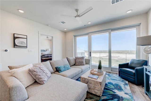 living room featuring ceiling fan, a water view, and light hardwood / wood-style floors