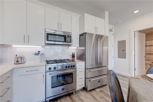 kitchen with electric panel, light wood-type flooring, backsplash, white cabinets, and high end appliances