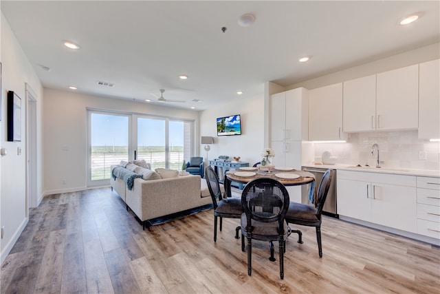 dining area with ceiling fan, sink, and light wood-type flooring