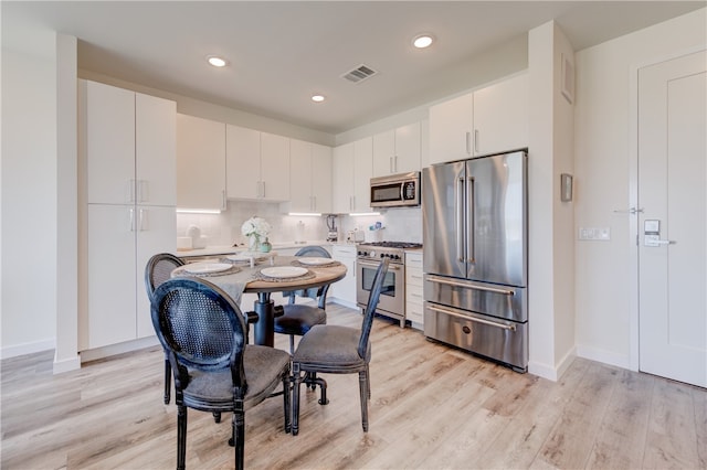 kitchen featuring white cabinets, decorative backsplash, light hardwood / wood-style flooring, and high quality appliances