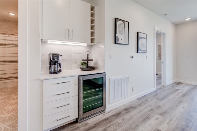 bar featuring light hardwood / wood-style floors, beverage cooler, white cabinetry, and tasteful backsplash