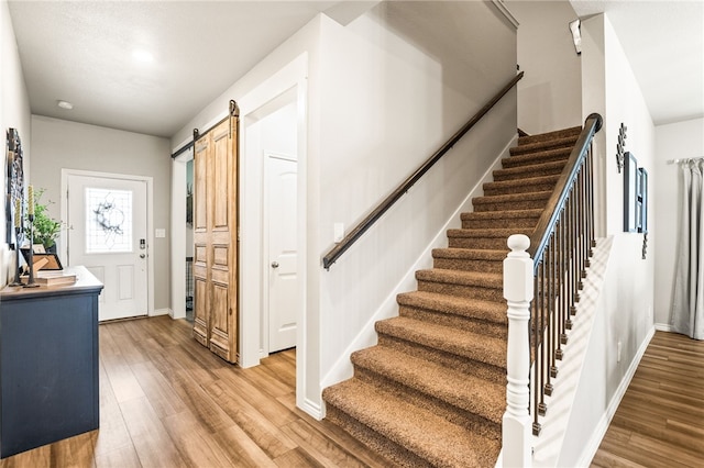 1345 Regents Park, Corpus Christi, TX 78415 - staircase featuring a barn door, wood finished floors, and baseboards