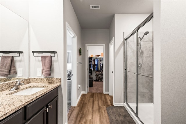 1345 Regents Park, Corpus Christi, TX 78415 - bathroom featuring wood finished floors, a shower stall, a walk in closet, vanity, and baseboards