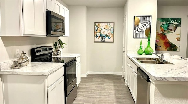 kitchen with stainless steel appliances, light hardwood / wood-style floors, sink, kitchen peninsula, and white cabinets