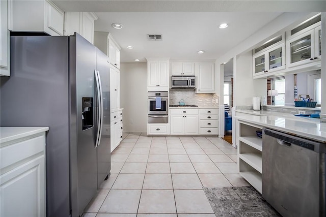 1703 Bayshores, Rockport, TX 78382 - kitchen featuring appliances with stainless steel finishes, a warming drawer, white cabinets, light tile patterned floors, and light countertops