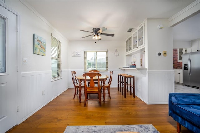 1703 Bayshores, Rockport, TX 78382 - dining area featuring a wainscoted wall, ceiling fan, ornamental molding, and light wood-type flooring