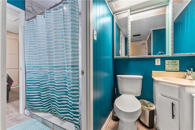 bathroom featuring vanity, wood walls, a shower with shower curtain, hardwood / wood-style flooring, and toilet