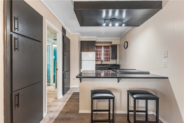 kitchen with a kitchen breakfast bar, kitchen peninsula, hardwood / wood-style floors, and white fridge