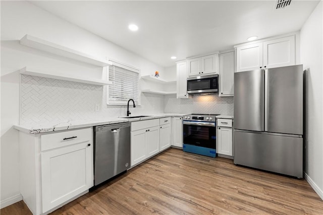 kitchen featuring appliances with stainless steel finishes, backsplash, sink, light hardwood / wood-style flooring, and white cabinets