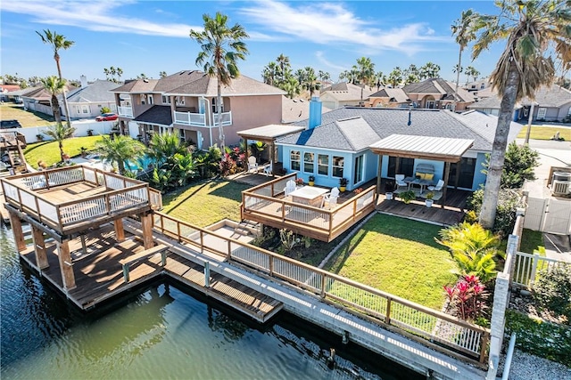 back of house featuring a residential view, a chimney, a deck with water view, and a yard