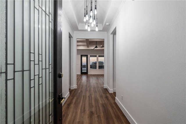 corridor featuring a notable chandelier, dark wood-type flooring, baseboards, ornamental molding, and a textured wall