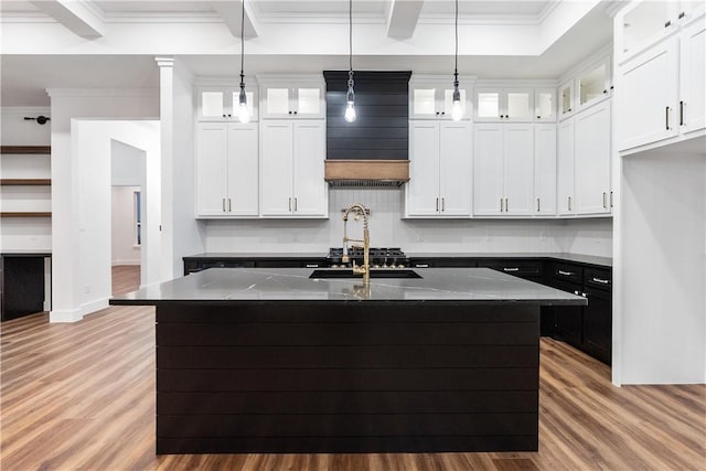 10 Westpointe Dr, Rockport, TX 78382 - kitchen featuring light wood-style floors, dark stone counters, a kitchen island with sink, white cabinets, and ornamental molding