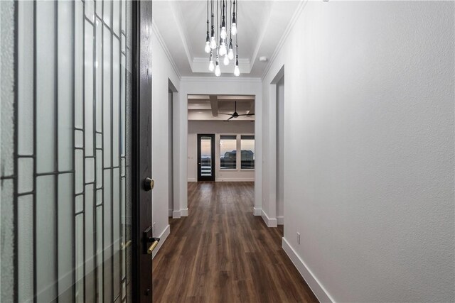 hallway with baseboards, ornamental molding, dark wood-type flooring, a textured wall, and an inviting chandelier