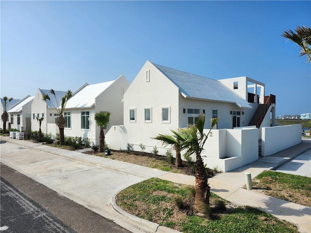 view of front facade with stucco siding, fence, and a residential view