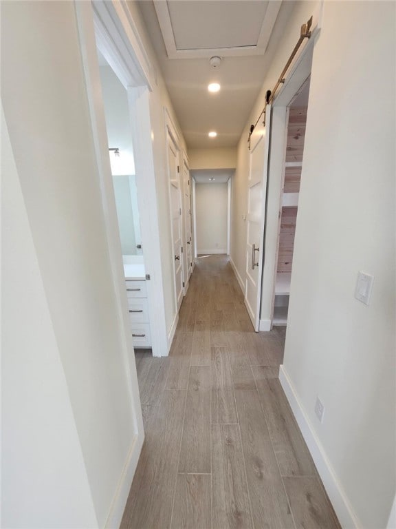 hall with baseboards, light wood-type flooring, and recessed lighting