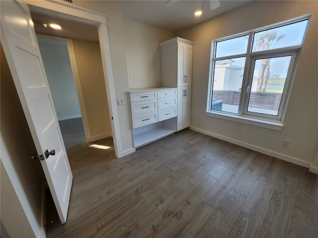 unfurnished bedroom with recessed lighting, dark wood-style flooring, and baseboards