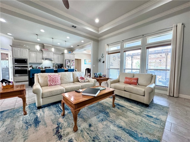 living room featuring ornamental molding, ceiling fan, and a tray ceiling