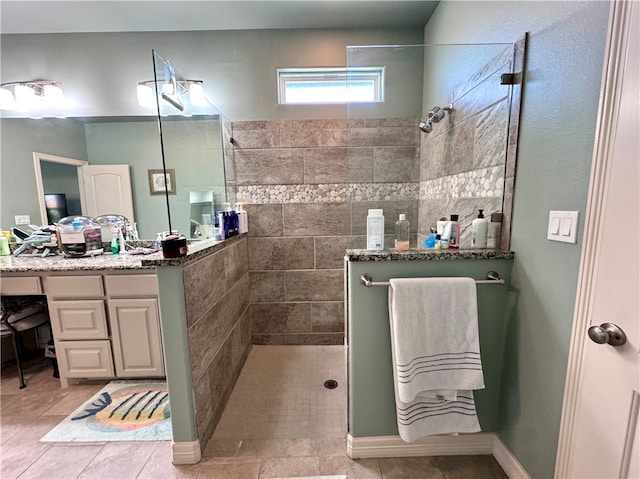 bathroom featuring tile patterned flooring, vanity, and a tile shower