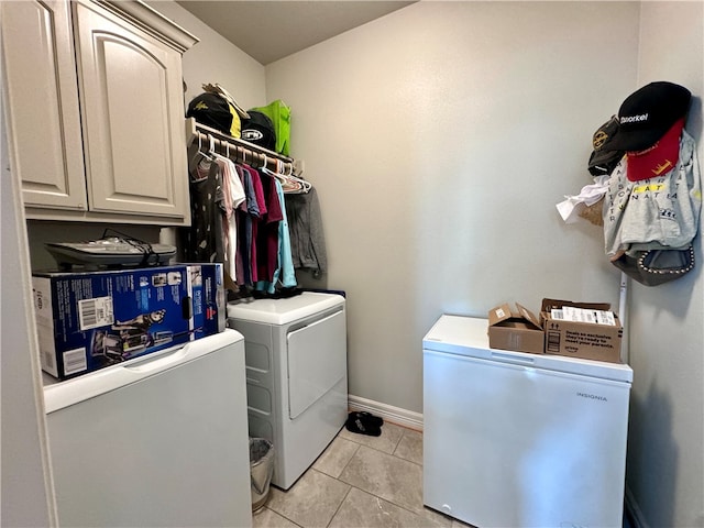 laundry area featuring washing machine and clothes dryer, cabinets, and light tile patterned floors