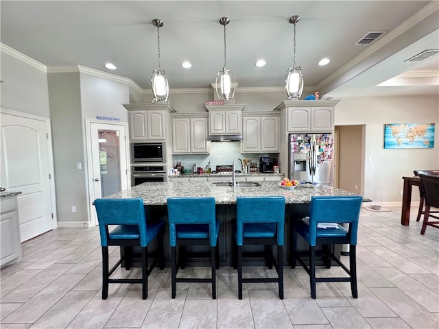 kitchen featuring light stone counters, a kitchen island with sink, appliances with stainless steel finishes, and ornamental molding