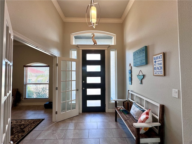 entryway featuring light tile patterned flooring, ornamental molding, and a towering ceiling