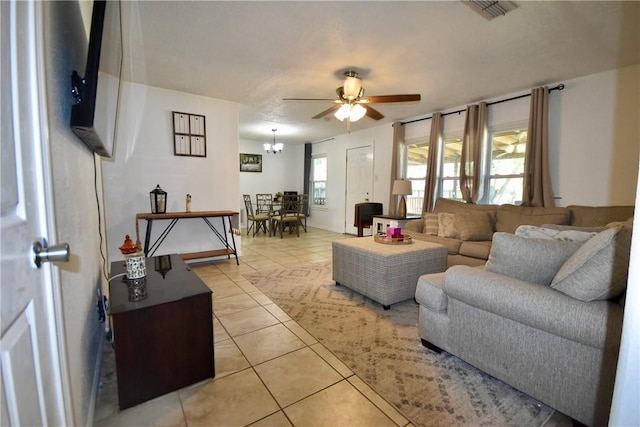 living area featuring light tile patterned flooring, visible vents, and ceiling fan with notable chandelier