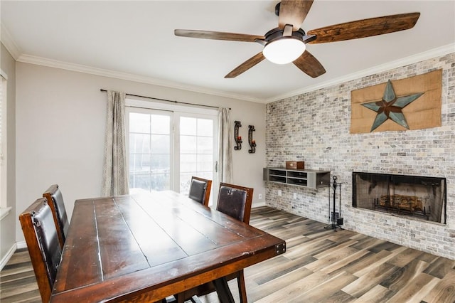 unfurnished dining area featuring a fireplace, ceiling fan, crown molding, and wood-type flooring