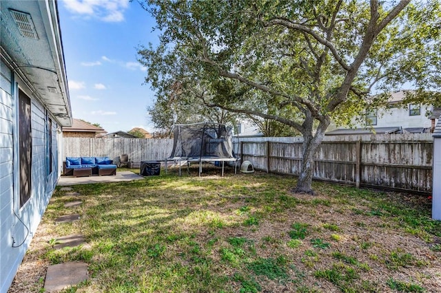 view of yard with a trampoline, an outdoor living space, and a patio area