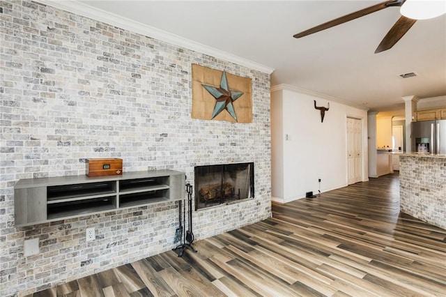 unfurnished living room featuring dark hardwood / wood-style flooring, ceiling fan, crown molding, and a brick fireplace