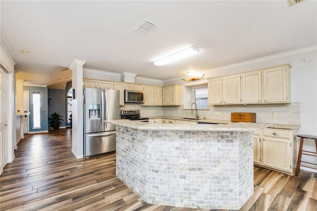 kitchen with ornamental molding, cream cabinets, stainless steel appliances, and a center island