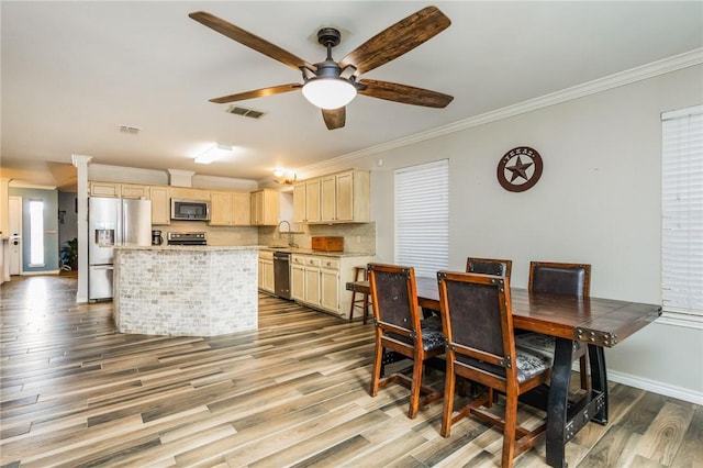 dining area featuring sink, crown molding, wood-type flooring, and ceiling fan