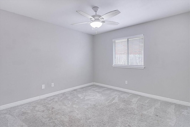 empty room with carpet, a ceiling fan, and baseboards