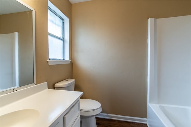 bathroom featuring toilet, vanity, hardwood / wood-style floors, and a bathing tub