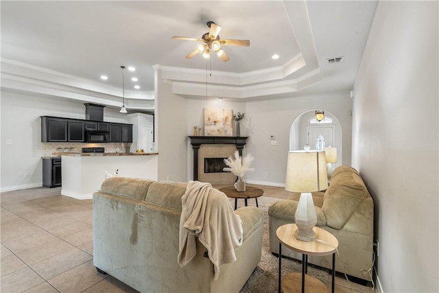 living room featuring recessed lighting, arched walkways, a tray ceiling, a ceiling fan, and light tile patterned floors