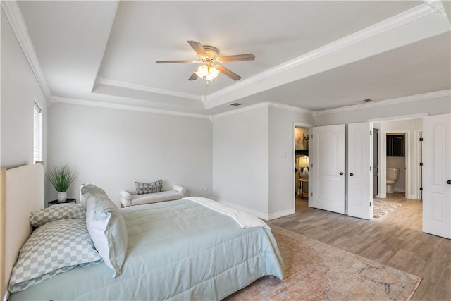 bedroom featuring a raised ceiling, baseboards, ornamental molding, and wood finished floors