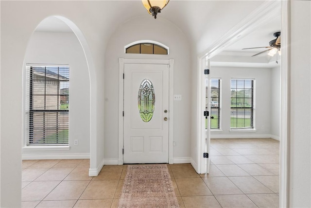 foyer entrance with baseboards, a ceiling fan, and light tile patterned floors