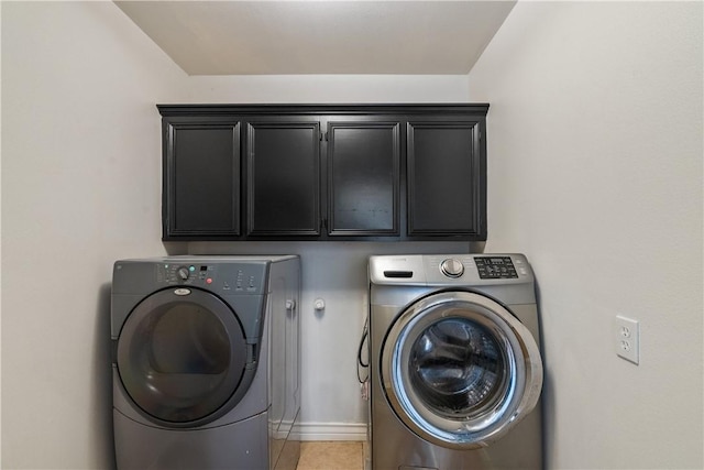 laundry area with cabinet space, light tile patterned flooring, baseboards, and washer and clothes dryer