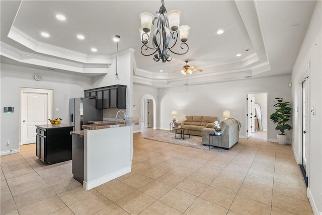 kitchen featuring arched walkways, a tray ceiling, stainless steel refrigerator with ice dispenser, and light tile patterned flooring