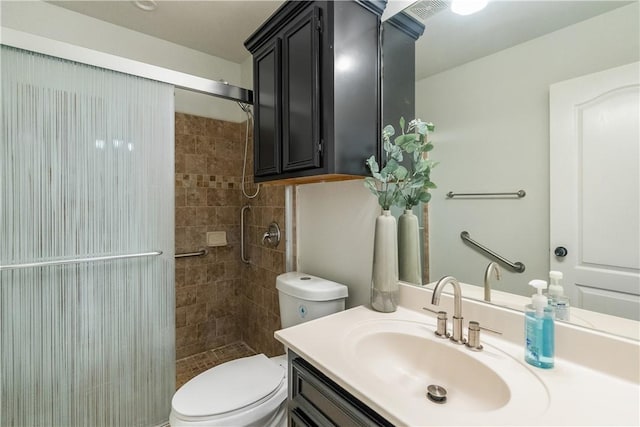 bathroom with vanity, a tile shower, toilet, and visible vents