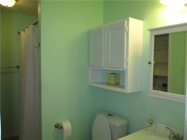 bathroom featuring curtained shower, sink, and toilet