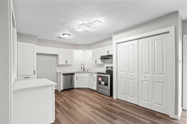 kitchen with hardwood / wood-style flooring, sink, stainless steel appliances, and white cabinets