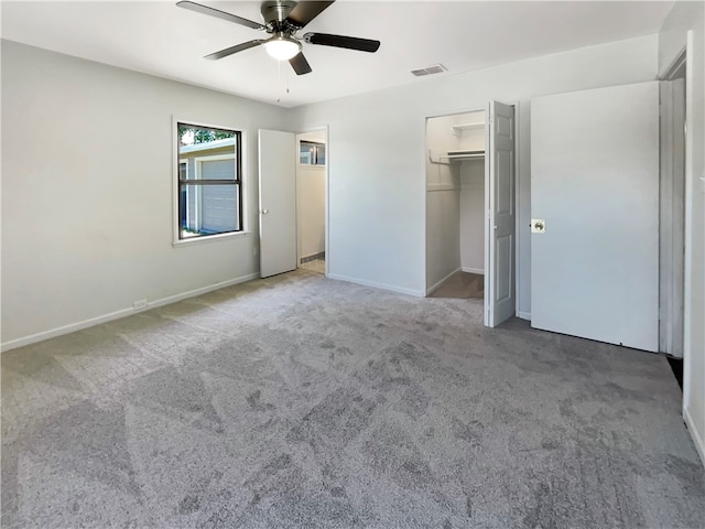 unfurnished bedroom with a closet, carpet, a walk in closet, and ceiling fan